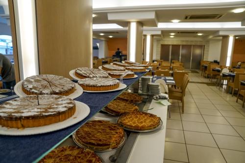 een rij taarten op een tafel in een cafetaria bij Futura Club Torre Rinalda in Torre Rinalda