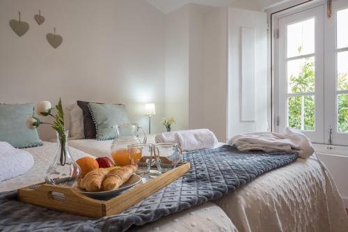 a tray of bread and glasses on a bed at Home at Évora's Main Street in Évora