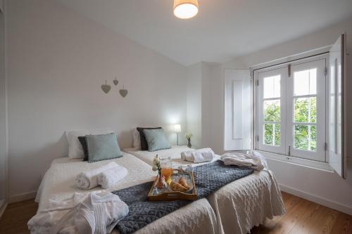 a white bedroom with a bed with a tray on it at Home at Évora's Main Street in Évora