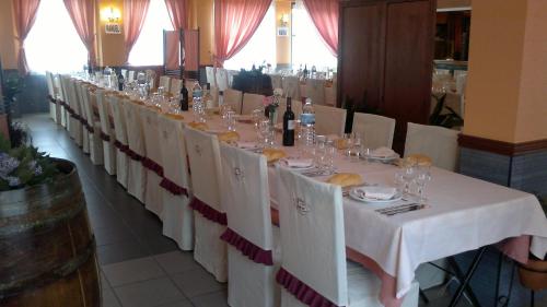 a long table with white chairs and wine bottles at Hostal Restaurante Solaire in Castañar de Ibor