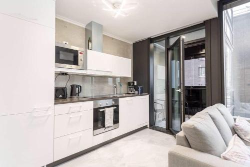 a kitchen with white cabinets and a couch in a room at Apartments with free parking in Oulu