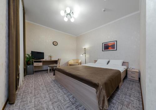 a hotel room with a large bed and a desk at Hotel Vizit in Cherepovets