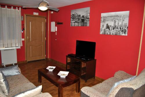 a living room with red walls and a flat screen tv at Apartahotel Rural CollaRubio Luxury in Collado Mediano