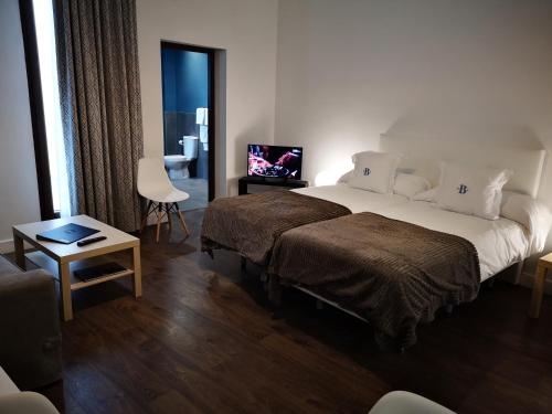 a hotel room with two beds and a television at Barroso Centro Aptos. in Córdoba