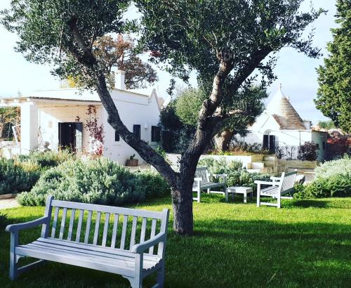 a white bench sitting in the grass next to a tree at Tenuta del Lauro in Locorotondo