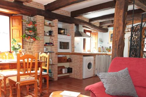 a living room with a red couch and a kitchen at Casa de Piedra in Valderrueda