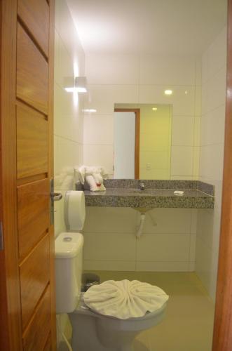 a bathroom with a toilet and a sink and a mirror at Pontal Praia Hotel in Porto Seguro