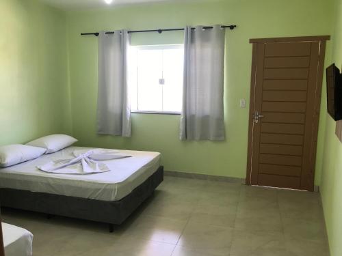 a bedroom with a bed and a window and a door at Residencial Veleiros Do Mar in Capão da Canoa