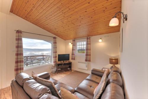 a living room with a couch and a large window at Appin Holiday Homes -Caravans, Lodges, Shepherds Hut and Train Carriage stays in Appin