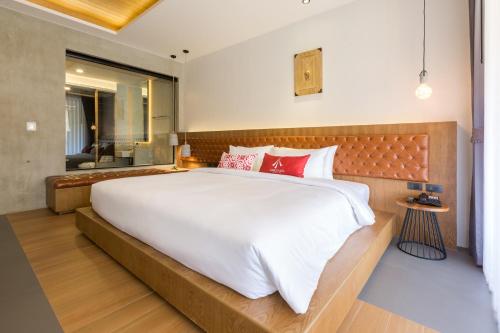 a bedroom with a large white bed with red pillows at Aurico Kata Resort & Spa - SHA Extra Plus in Kata Beach