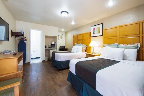 a hotel room with two beds and a desk at Travel Lodge by Wyndham Merced Yosemite in Merced