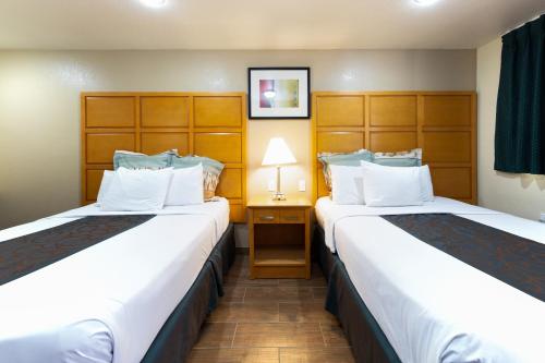 a hotel room with two beds and a lamp at Travel Lodge by Wyndham Merced Yosemite in Merced