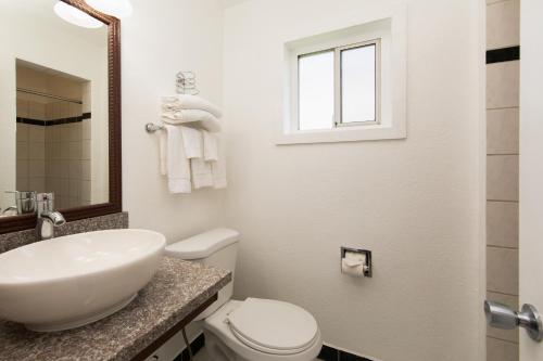a white bathroom with a sink and a toilet at Travel Lodge by Wyndham Merced Yosemite in Merced