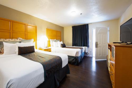 a hotel room with two beds and a flat screen tv at Travel Lodge by Wyndham Merced Yosemite in Merced