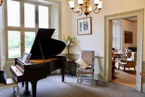 a living room with a piano and a chair at Grafton Manor Hotel in Bromsgrove