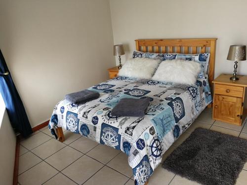 um quarto com uma cama com um edredão azul e branco em The White House Apartment em Mossel Bay