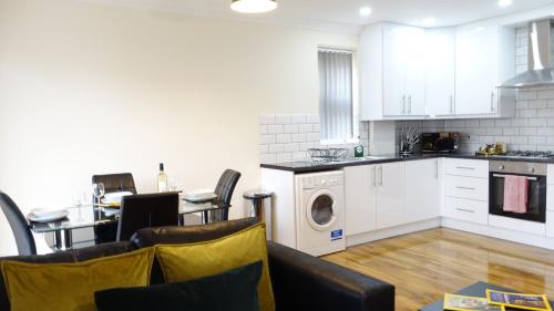 a kitchen with white cabinets and a washer and dryer at Lux 2 Bedroom 2 Bathroom APT at HEATHROW AIRPORT- free parking- Near The terminals-Easy access to Central London- Family Friendly in Stanwell