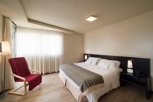 1 dormitorio con 1 cama grande y 1 silla roja en 27 Suites Hotel, en Montevideo