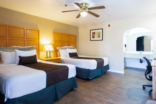 a hotel room with two beds and a ceiling fan at Travelodge by Wyndham Merced Yosemite in Merced