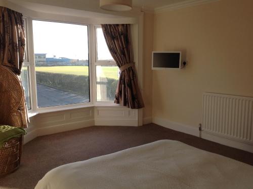 a bedroom with a window and a bed and a tv at Cricket View cottage in Redcar