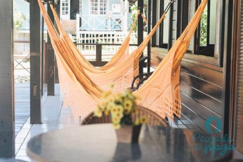 a hammock on a porch with a vase of flowers at Pousada da Maga in Fernando de Noronha