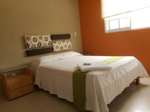 a bedroom with a bed with white sheets and a window at Hermosa Casa Acapulco Diamante Hospedaje a 5 min de la playa in Acapulco
