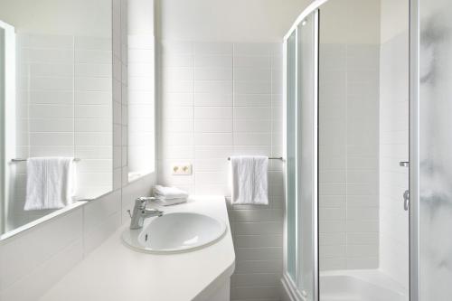 a white bathroom with a sink and a shower at Century Hotel Antwerpen Centrum in Antwerp