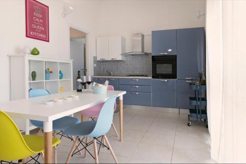 a kitchen with blue cabinets and a white table and chairs at Casa Te Mare in Torre Suda
