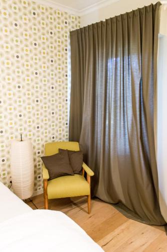 a bedroom with a yellow chair and a curtain at Mon Dieu in Scherpenheuvel-Zichem
