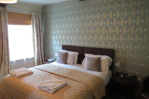 a bedroom with a bed with white sheets and pillows at The Kings Head Hotel in Ross on Wye