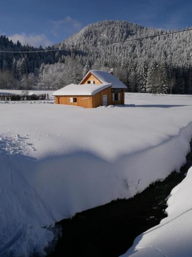 a house in a snow covered field with a building at Chalet pour amoureux de la nature avec vue sur le lac de Retournemer in Xonrupt-Longemer