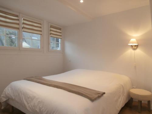 a white bed sitting under a window next to a lamp at au Claire de lune in Dieppe