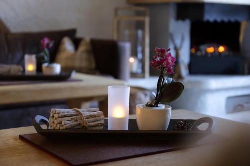 a tray with a candle and a vase with flowers and bread at Boutique Hotel Längenfelder Hof in Grainau