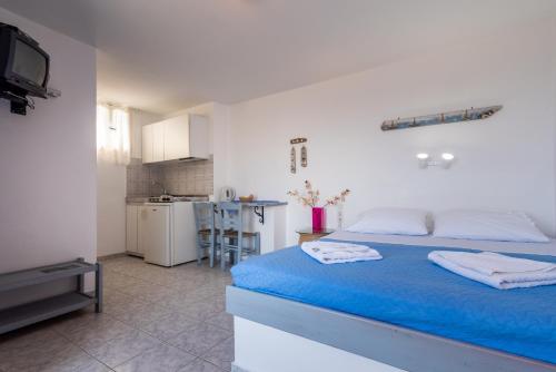 a bedroom with a blue bed and a kitchen at Polyegos View in Pollonia