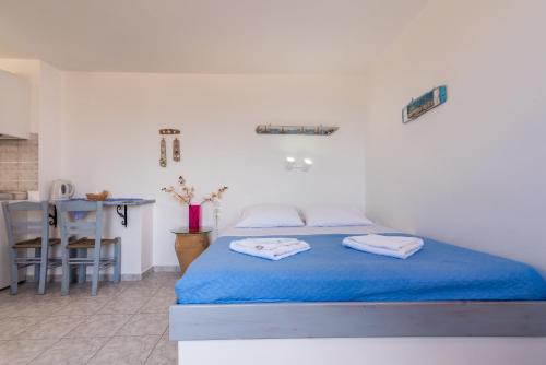 a bedroom with a bed with blue sheets and a table at Polyegos View in Pollonia