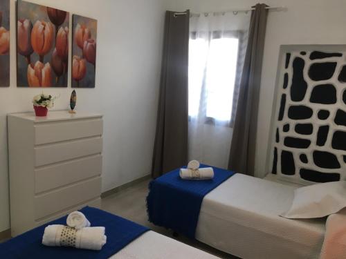 a bedroom with two beds and a dresser and a window at Casa Gloria in Tías