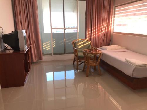 um quarto com uma cama, uma mesa e cadeiras em Paradorn Inn em Chumphon