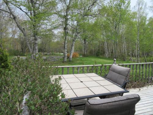 a patio with a table and chairs on a deck at Maggie's Place on the Cabot Trail in Birch Plain