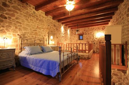 a bedroom with a bed and a stone wall at Lithos Traditional Guest Houses in Xerokampos