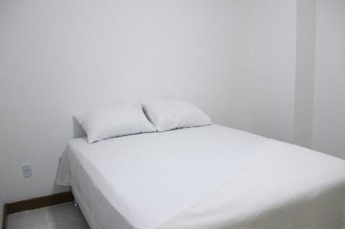 Una cama blanca con dos almohadas encima. en Residencial Copa 1, en Río de Janeiro