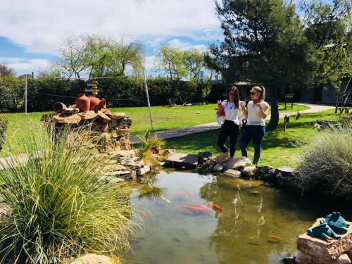 two women standing in front of a koi pond at Complejo Turistico Los Troncos in San Rafael
