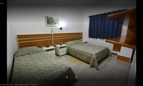 a hotel room with two beds and a window at Hotel Xapuri in Peruíbe