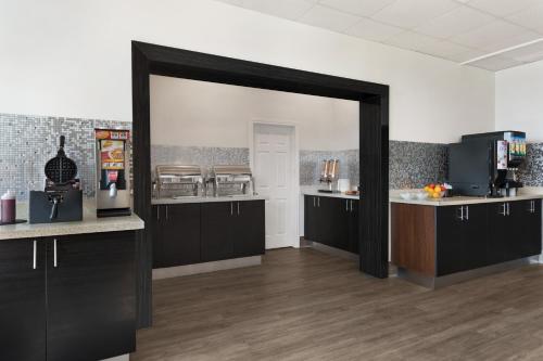 a kitchen with black cabinets and a large mirror at Ramada by Wyndham Belleville Harbourview Conference Center in Belleville