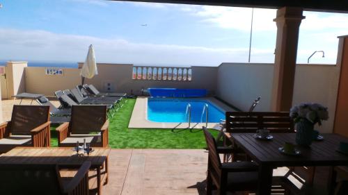 a patio with a pool and tables and chairs at Villa Mia in Caleta De Fuste