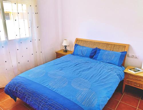 Schlafzimmer mit einem blauen Bett und einem Kopfteil aus Holz in der Unterkunft AOTEAROA in La Azohía
