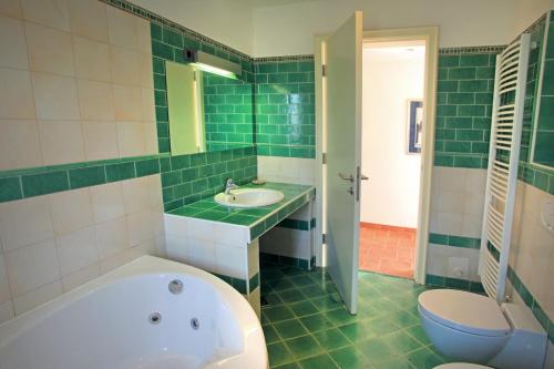a green tiled bathroom with a tub and a sink at Spacious Villa in Parecag with a Swimming Pool in Sečovlje