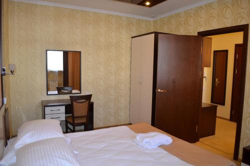 a bedroom with a bed and a dresser and a desk at Mereke Hotel in Ustʼ-Kamenogorsk