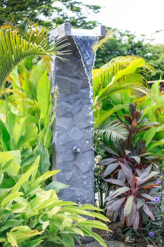 a stone pillar in a garden with plants at Lua Villas in Santa Teresa Beach