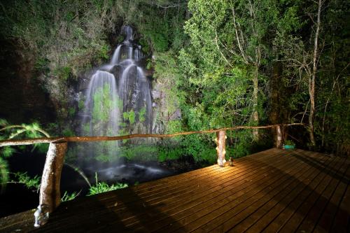 a waterfall in a forest with a wooden bridge at Pucura Eco Lodge in Licán Ray