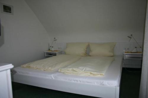 a white bed in a room with two tables at Hotel Café Talblick in Vielbrunn